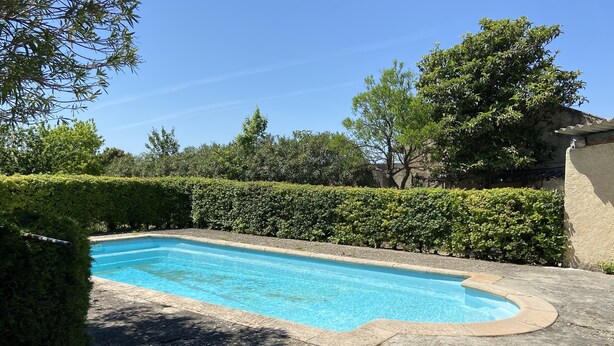 A rectangular swimming pool with a stone border, surrounded by well-maintained hedges and trees. - Country house ! 5 minutes from the village center. (Caromb)