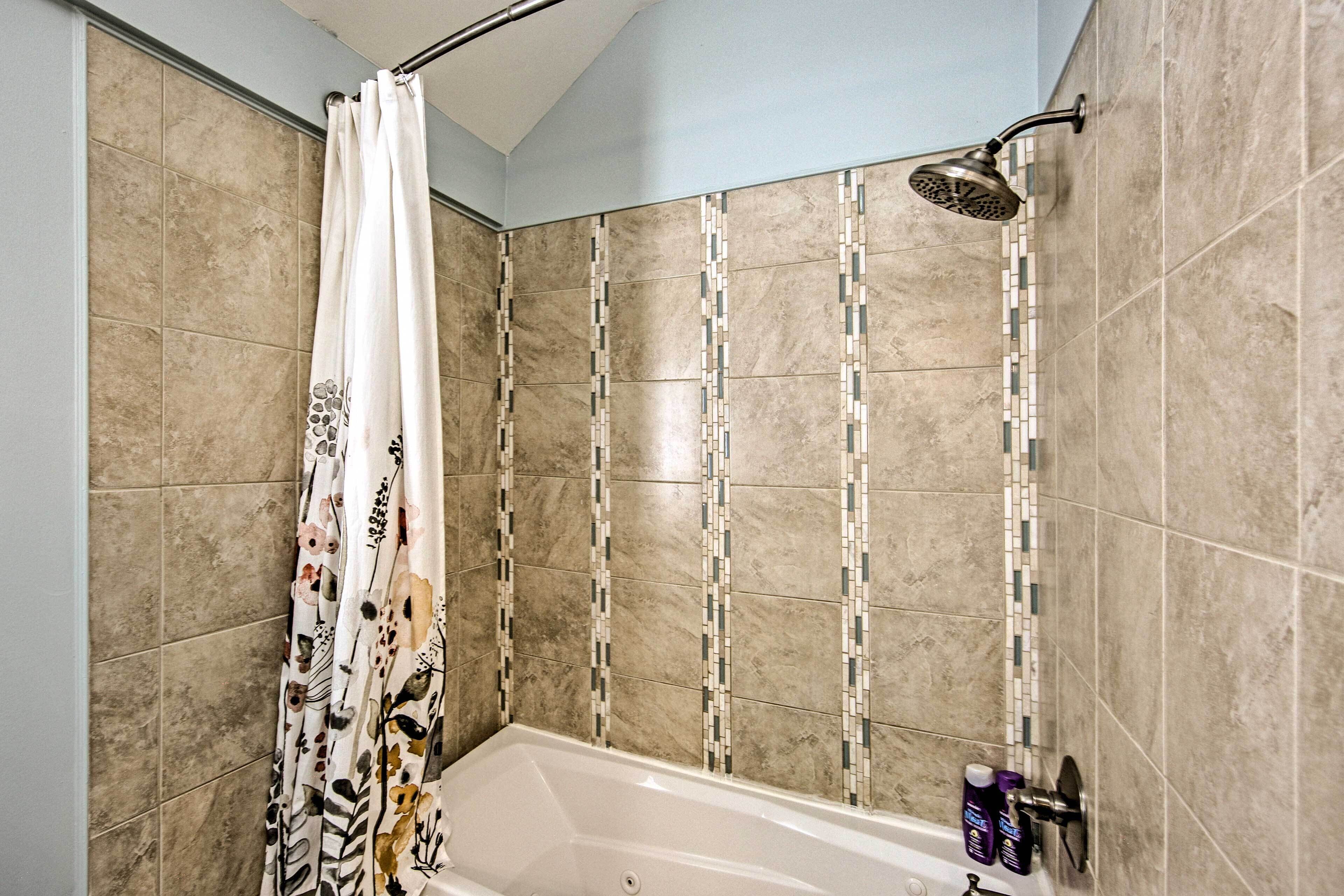 Une salle de bain avec une douche, une baignoire et un mur carrelé.