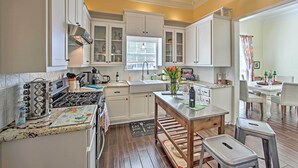 Una cocina con armarios blancos, una estufa y una zona de comedor con una mesa y sillas.