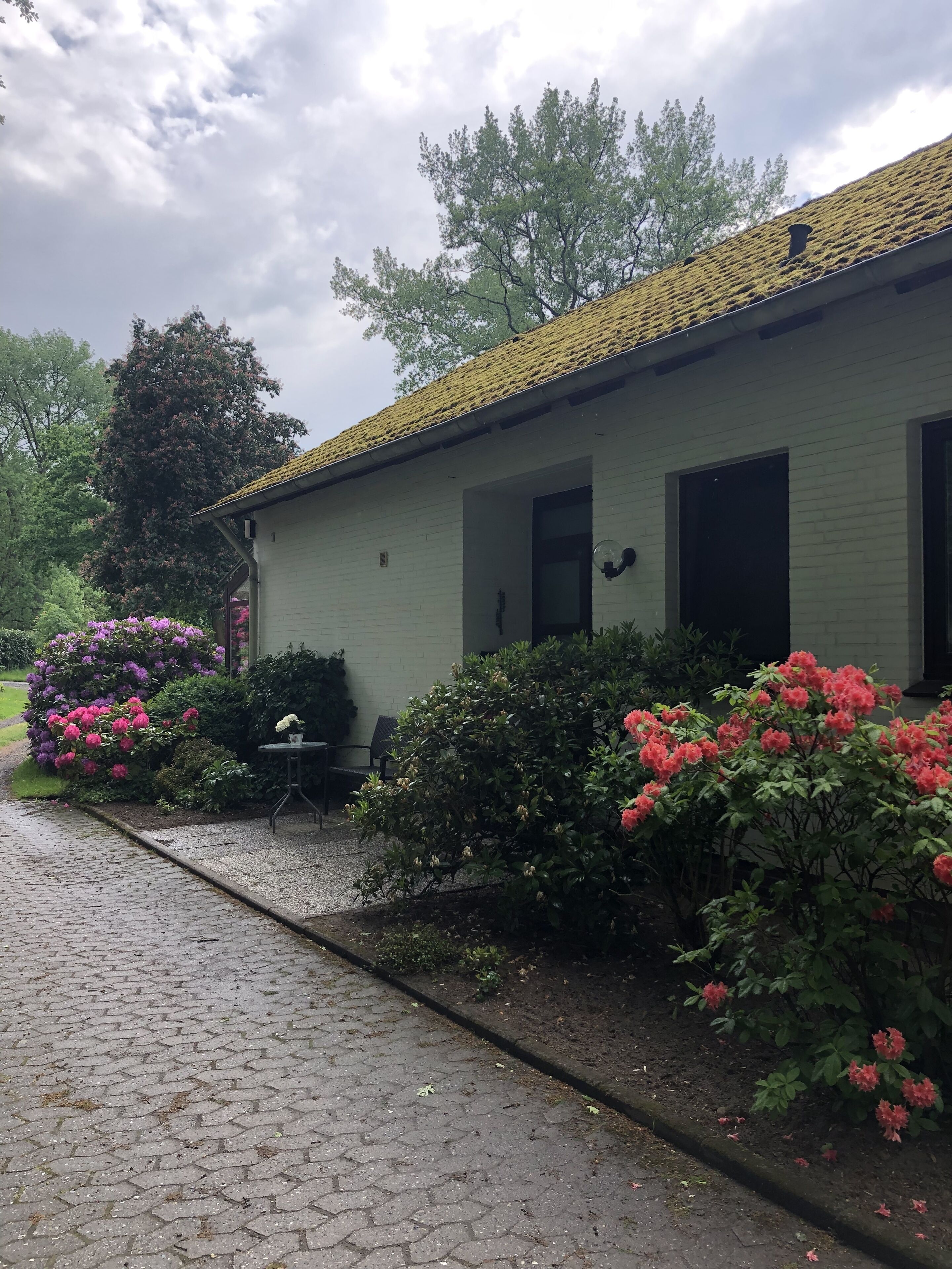 A building with a tiled roof, a brick wall, and a paved entrance.