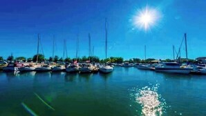 A marina with multiple boats docked, clear skies, and a bright sun. - Face a le Mer Fleury (Fleury)
