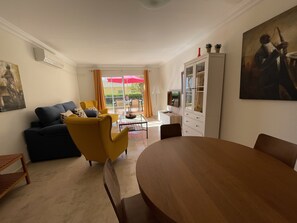 A living room with a sofa, armchairs, a dining table, and a cabinet.