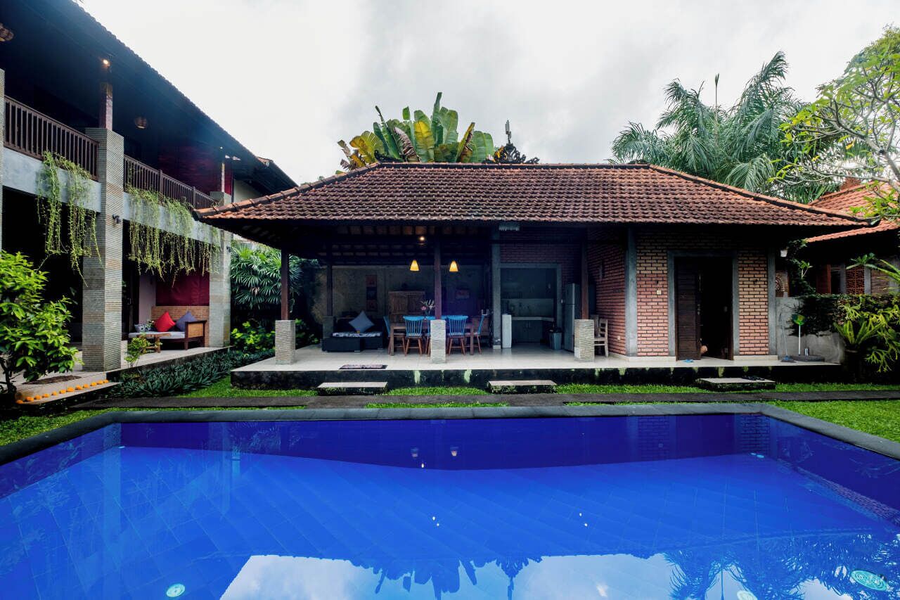 Uma casa com piscina, varanda coberta e área de estar, e um jardim.