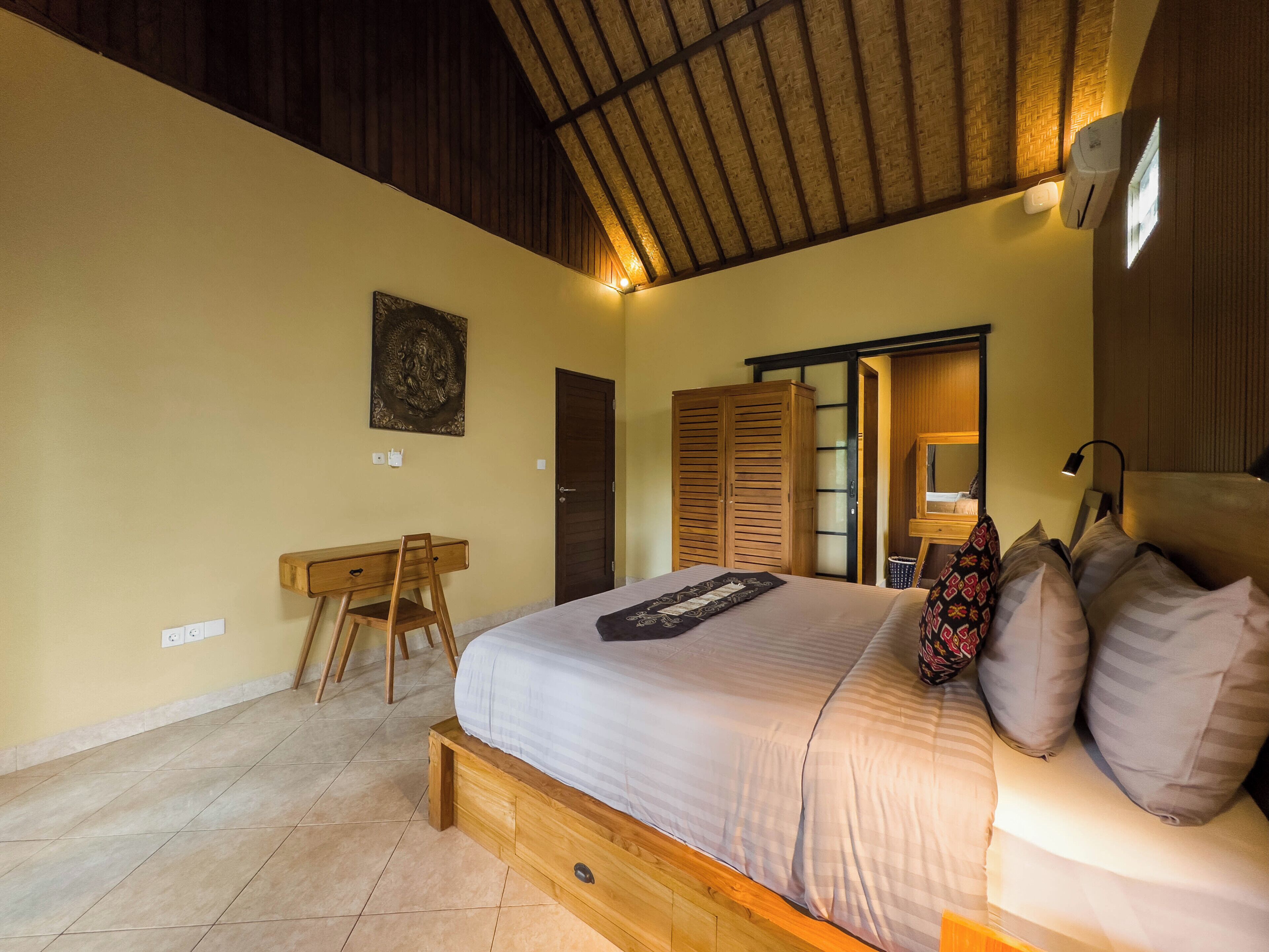 A bedroom with a large bed, wooden desk, and wardrobe.