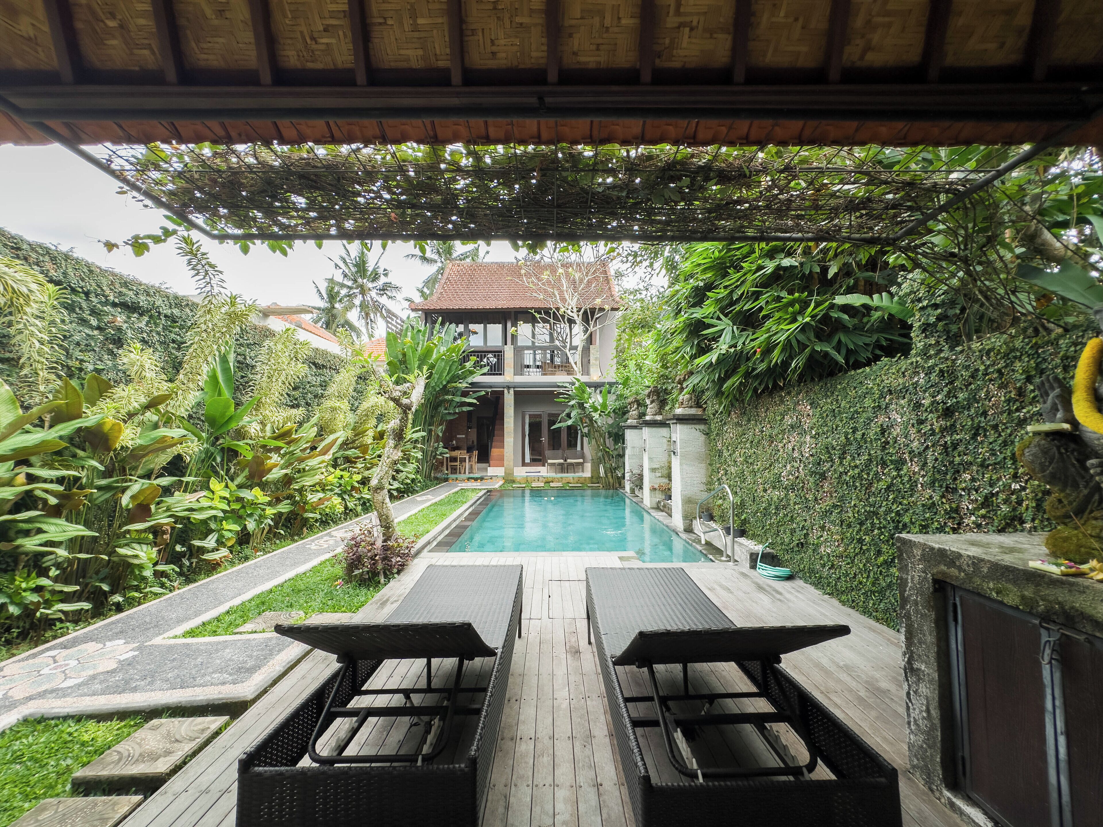 A pool area with two lounge chairs and a wooden deck.