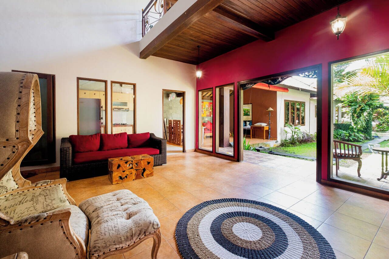 A spacious living area with a red sofa, a wooden coffee table, and a patterned rug.