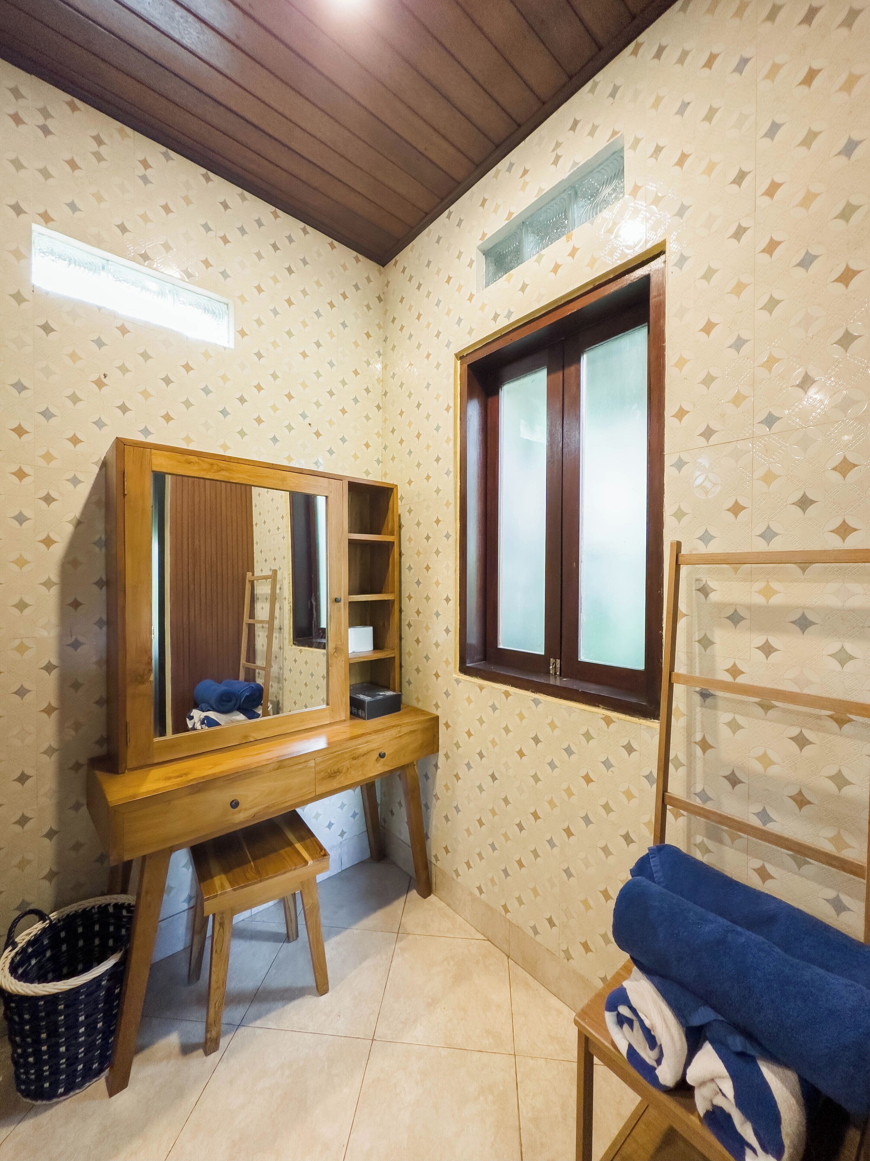 A room with a wooden vanity, a mirror, a window, and a towel rack.