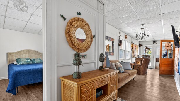 A room with a bed, a sofa, a wooden console table, a mirror, and a television.