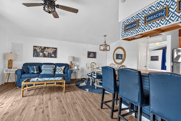Un salon avec un canapé bleu, une table basse en bois et un coin repas avec des chaises bleues.
