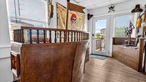 A wooden bar area with a wooden railing, a door leading outside, and nautical-themed decorations.