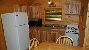 Une cuisine de taille réduite, dotée de meubles en bois, d’un réfrigérateur, d’un four à micro-ondes, d’un évier et d’une cuisinière.