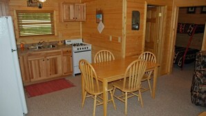 L’intérieur d’une cabane en bois comprend un coin cuisine, une table à manger et des chaises.