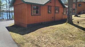 Une cabane en bois avec un toit en pente, un porche à l’avant et une petite terrasse.