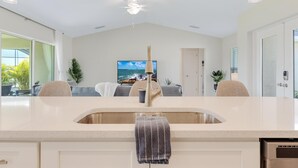 A modern kitchen with a large island, a built-in sink, and pendant lighting. - The Charm of a sand castle, creative & artisitc, Waterfront - Villa Sand Castle - Roelens Vacations (Cape Coral)