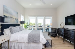 Une chambre moderne dotée d’un grand lit, d’une télévision, d’un bureau et d’un balcon avec vue.