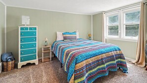Um quarto com uma cama, penteadeira, janela e luminária no teto.