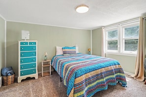 A bedroom with a bed, a dresser, a window, and a ceiling light.