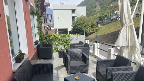 An outdoor patio with wicker furniture, a small table, and a view of a hillside.
