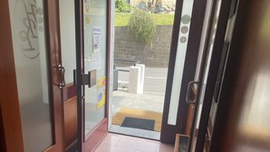 An entrance with a glass door, a tiled floor, and a small mat at the entrance.