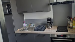 Ett kompakt kök med en diskho, en kaffebryggare, en brödrost och en spis.