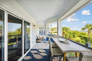 A balcony with a dining area, a sliding glass door, and a view of the landscape. - Beautiful Spacious Oceanfront Condo On Isle of Palms (Isle of Palms)