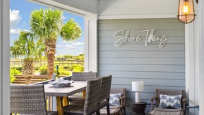 A patio with wicker furniture, a table with a bottle, and a neon sign that reads "Shore Thing". - Beautiful Spacious Oceanfront Condo On Isle of Palms (Isle of Palms)