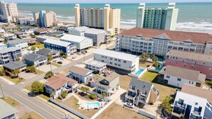 A coastal residential area with various buildings, including a large hotel with multiple balconies and a swimming pool. - Private Beach House, Pet Friendly, Close To Beach + Free Attraction Tickets! (North Myrtle Beach)