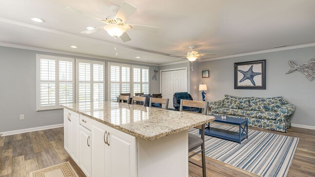 A spacious kitchen with a large island, a dining area with chairs, and a living room with a sofa and a starfish decoration. - Private Beach House, Pet Friendly, Close To Beach + Free Attraction Tickets! (North Myrtle Beach)