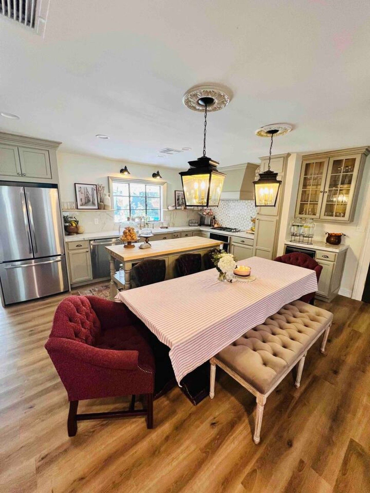 A kitchen with a central island, wooden flooring, and a dining area with a bench and chair.