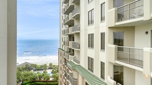 Un hotel de varios pisos con balcones que dan a una playa y zona de piscina.