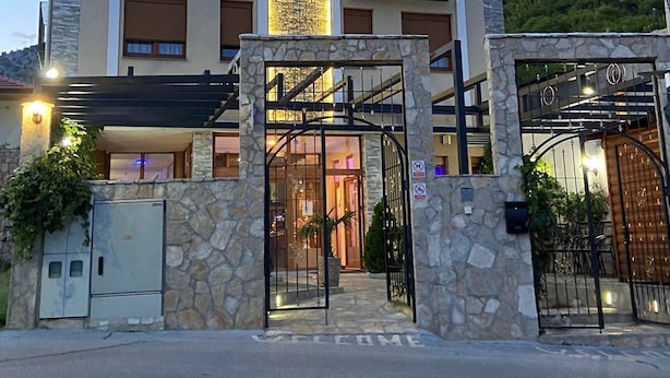 A multi-story hotel with a central illuminated tower, stone facade, and a welcoming entrance. - Hotel Blagaj (Mostar)
