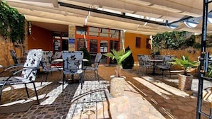 An outdoor patio area with stone flooring, patterned chairs, and potted plants. - Hotel Blagaj (Mostar)