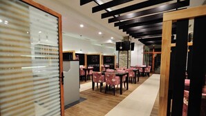 A restaurant with wooden flooring, pink floral chairs, and black and wooden ceiling beams. - Hotel Blagaj (Mostar)