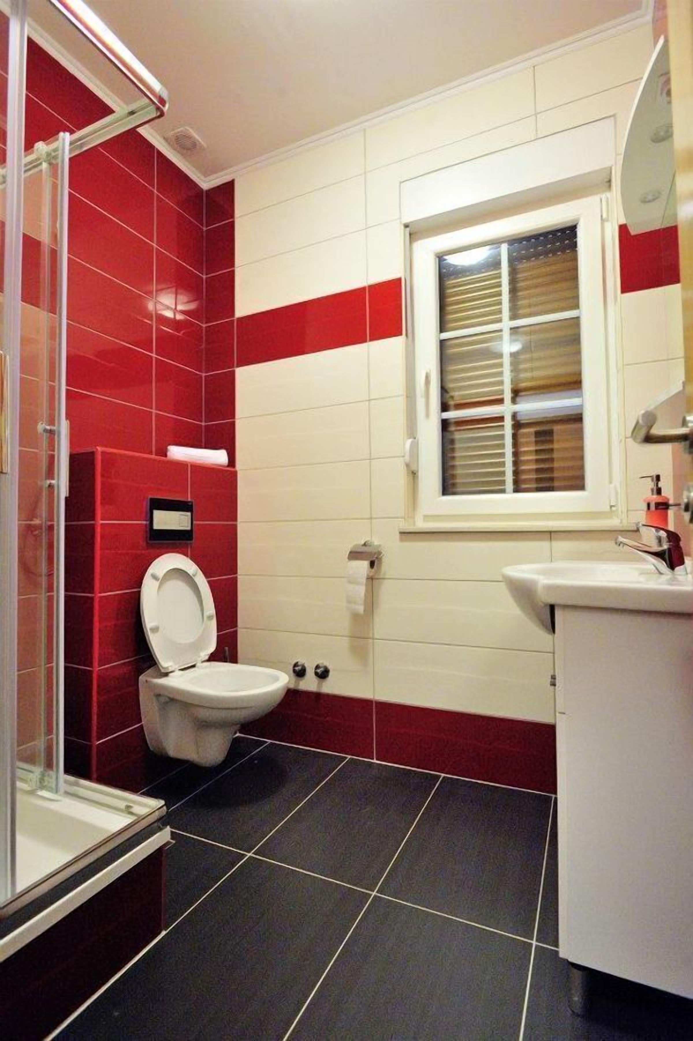 A bathroom with a toilet, a sink, and a window.