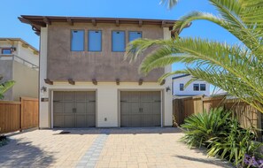 A two-story house with a garage, a wooden fence, and a paved driveway. - Retreat to Avila Beach Luxe, short stroll to ocean (Avila Beach)