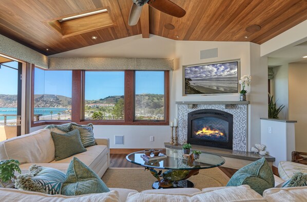 A spacious living room with a fireplace, large windows overlooking a scenic view, and a cozy seating area. - Retreat to Avila Beach Luxe, short stroll to ocean (Avila Beach)
