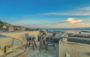 A terrace with a table and chairs, overlooking a coastal view with a pier. - Retreat to Avila Beach Luxe, short stroll to ocean (Avila Beach)