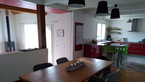 Een eethoek met een houten tafel en stoelen, een keuken op de achtergrond en een spatwand met rode en witte stippen.