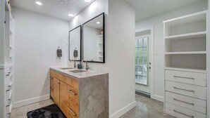 Une salle de bain moderne avec un meuble-lavabo à deux vasques, un grand miroir et un dressing avec de nombreux tiroirs.