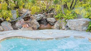 A hot tub surrounded by rocks and foliage.