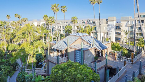 A multi-story hotel with balconies, a pool area, and lush greenery.