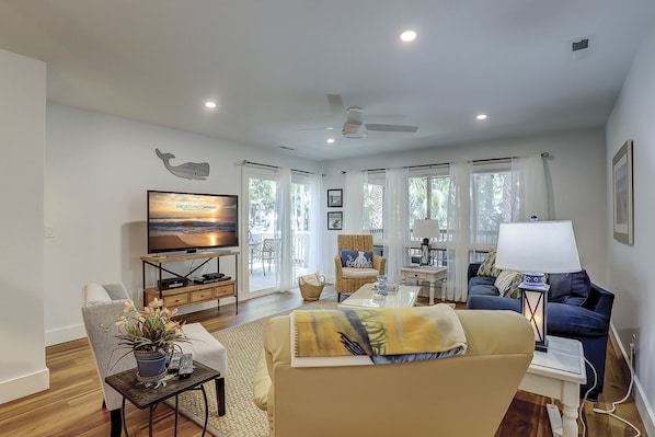 A spacious living room with a television, comfortable seating, and a view of the outdoors.