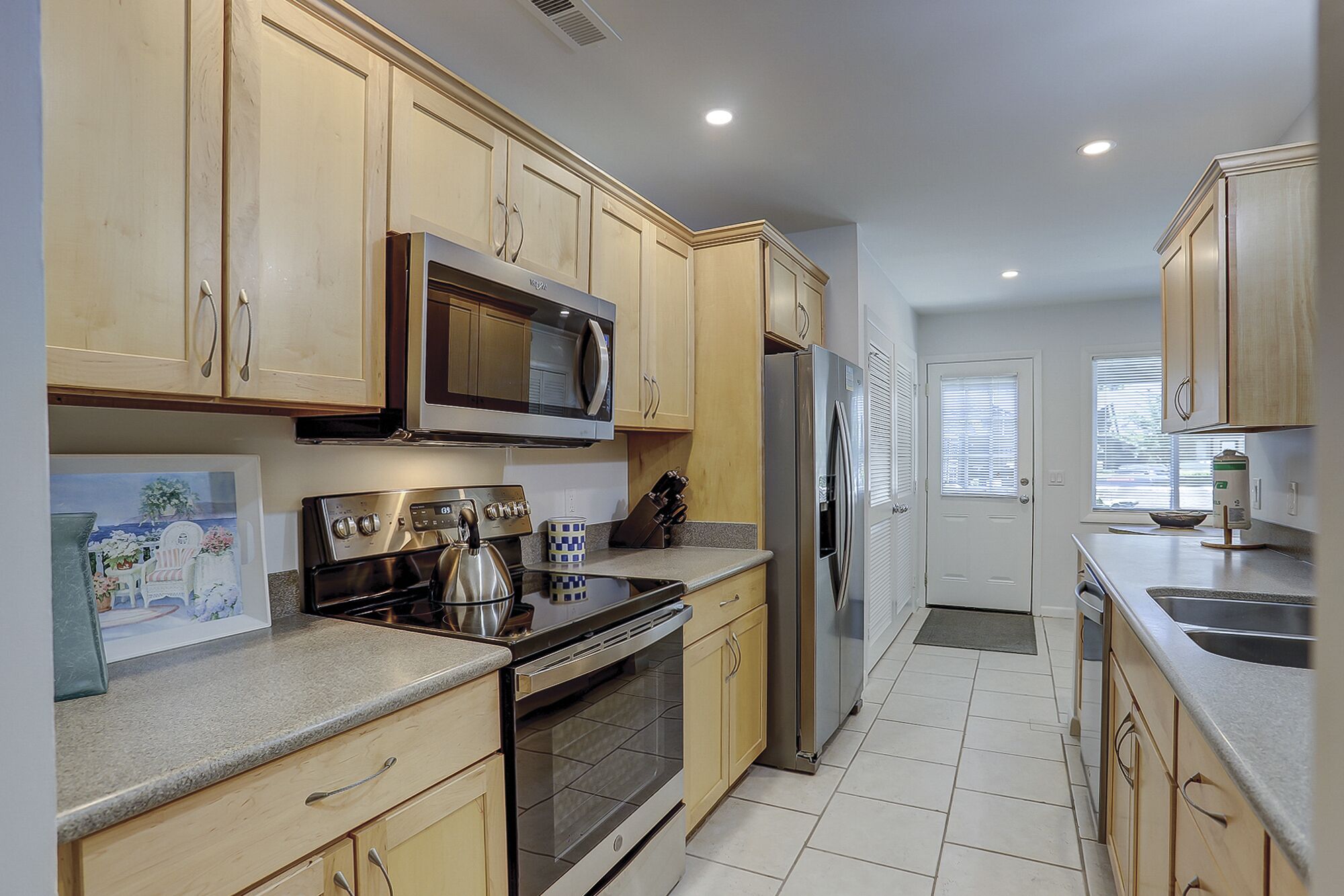 A kitchen with wooden cabinets, stainless steel appliances, a microwave, oven, and refrigerator.