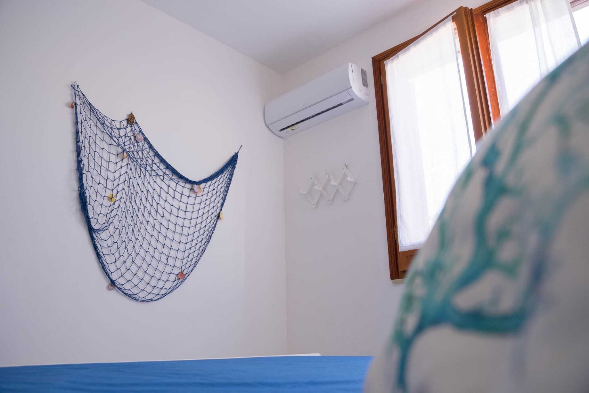 A room with a hammock, an air conditioning unit, and a window with curtains.