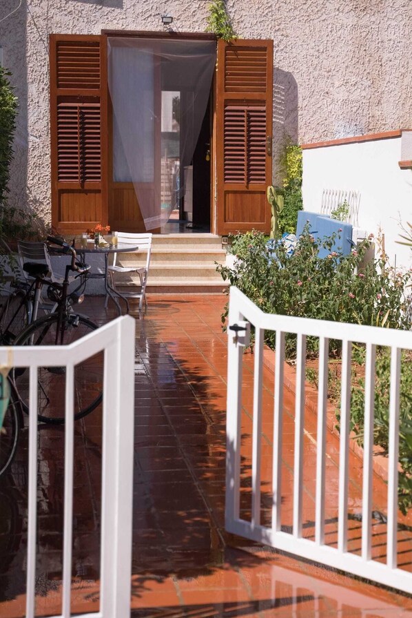 A courtyard with a white gate, a table with chairs, and a bicycle.