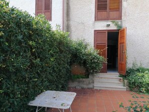Une cour avec une table en métal, une porte en bois et un mur blanc.