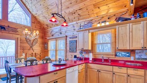 A wooden cabin interior with a kitchen, dining area, and large windows. - 3 Bedroom, Beautiful Mountain Views, Wireless Internet, Located behind MVCC (MAGGIE VALLEY)