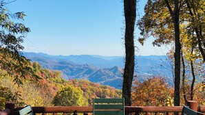A wooden deck with a table and chairs overlooking a mountainous landscape. - 3 Bedroom, Beautiful Mountain Views, Wireless Internet, Located behind MVCC (MAGGIE VALLEY)