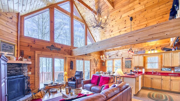 A cozy cabin interior with a fireplace, leather sofa, dining area, and kitchen. - 3 Bedroom, Beautiful Mountain Views, Wireless Internet, Located behind MVCC (MAGGIE VALLEY)