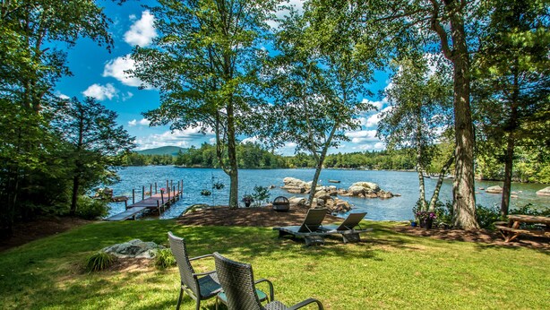 A lakeside view with a dock, lounge chairs, and a picnic table.